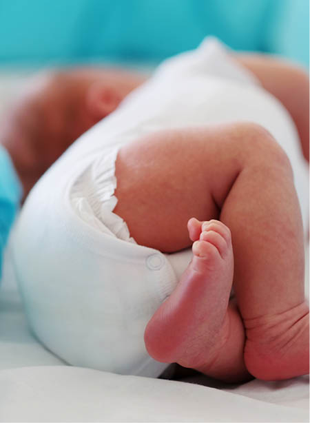 Two weeks old newborn baby's legs and bottom in diaper